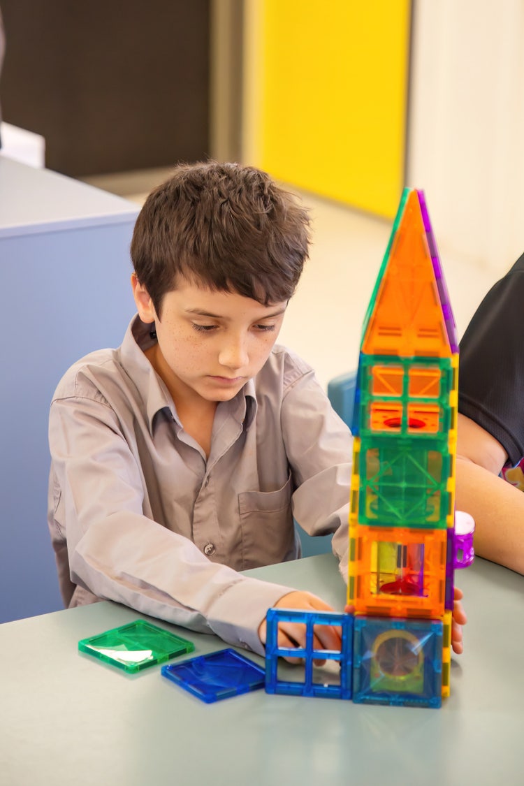 A student constructing a tower with play materials.